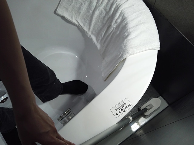 balnea 浴槽奥を柄のついたブラシなどで清掃の様子